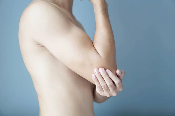 Närbild man hand Holding armbåge med smärta med blå bakgrund, hälsovård och medicinska koncept — Stockfoto