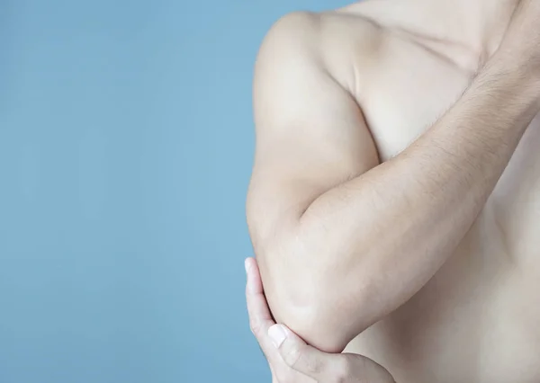 Closeup mão homem segurando cotovelo com dor com fundo azul, cuidados de saúde e conceito médico — Fotografia de Stock