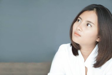 Yatak odasında yatakta oturan, düşünceli ya da depresif, seçici odaklı bir kadın.