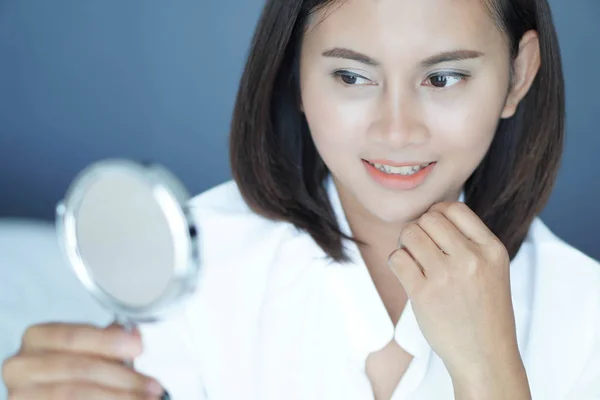 Cara cercana de la mujer mirando el espejo con sensación feliz, cuidado de la salud y concepto de belleza — Foto de Stock