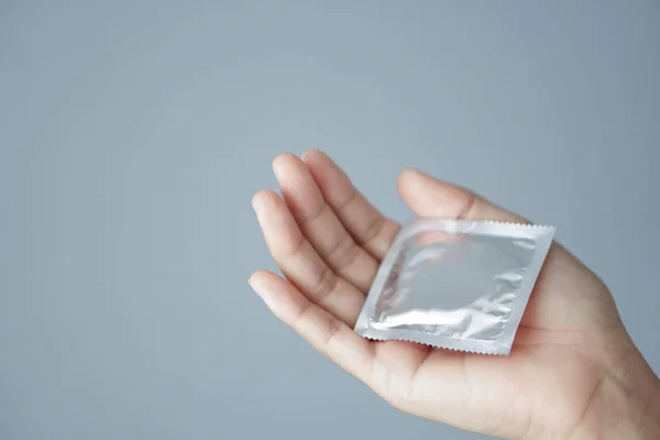 Крупним планом жінка тримає презерватив лежачи на білому ліжку, охорону здоров'я та медичну концепцію — стокове фото