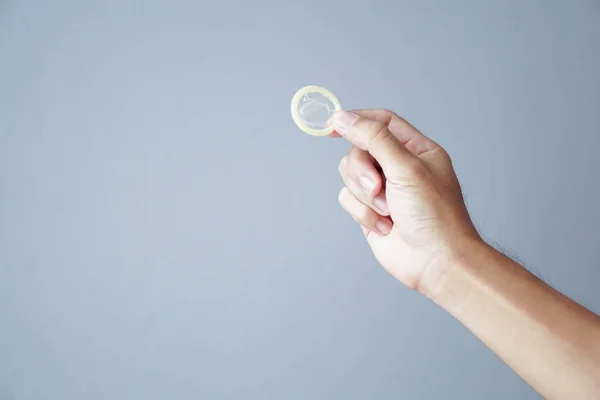 Close up homem mão segurando preservativo com fundo cinza, cuidados de saúde e conceito médico — Fotografia de Stock