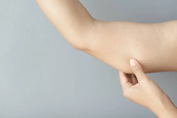 Zbliżenie kobieta ręka sprawdzanie ramię na szarym tle opieki zdrowotnej i koncepcji medycznej — Zdjęcie stockowe