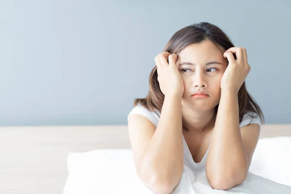 Closeup woman sitting on bed in the bedroom with thinking or depressed feeling, selective focus — Stock Photo, Image