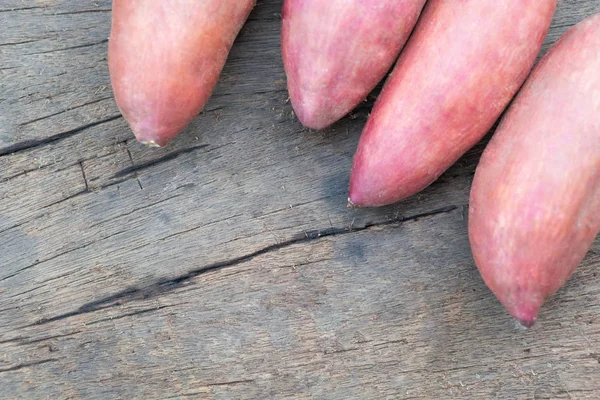 Rohe Süßkartoffeln auf Holztisch, gesundes Ernährungskonzept — Stockfoto