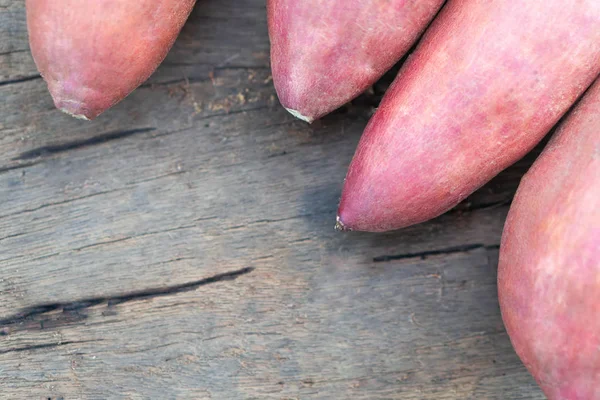 Rohe Süßkartoffeln auf Holztisch, gesundes Ernährungskonzept — Stockfoto