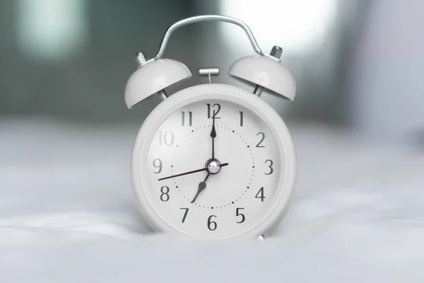 Ξυπνητήρι σε λευκό κακό για τον χρόνο αφύπνισης με φως από το παράθυρο, επιλεκτική εστίαση — Φωτογραφία Αρχείου