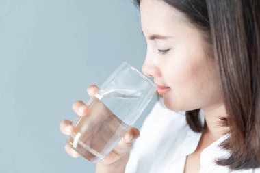 Sabahları cam bardaktan saf su içen, seçici odaklı bir kadın.