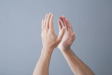 Gri arka planda el çırpan adam