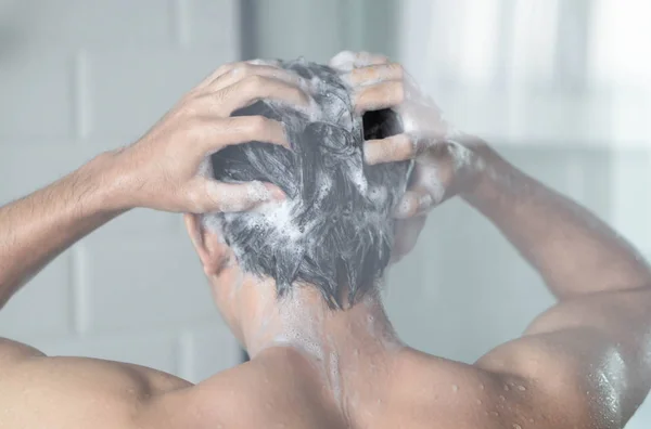 Closeup jovem homem lavar o cabelo com xampu no banheiro, tom vintage, foco seletivo — Fotografia de Stock