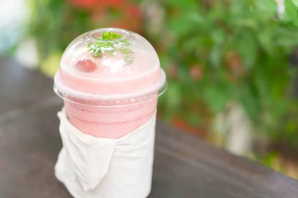 Närbild jordgubbs smoothie med grön natur bakgrund, selektiv fokus — Stockfoto