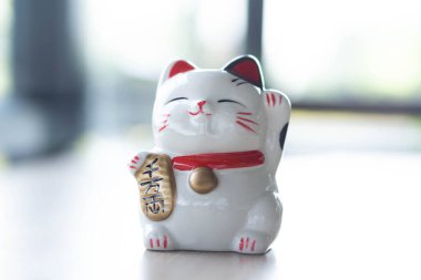 Maneki neko şanslı kedi elimizdeki metni gösterir yani ahşap masa zemininde zengindir, odak noktasını seçin