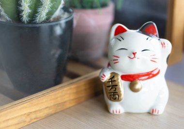 Maneki neko şanslı kedi elimizdeki metni gösterir yani ahşap masa zemininde zengindir, odak noktasını seçin