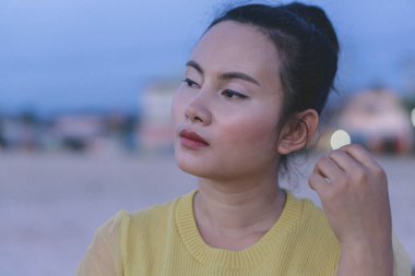 Asyalı kadın portresi. Mavi arka planda paylaşıyor ve düşünüyor.