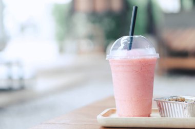 Yakın plan çilekli smoothie ve yeşil doğa arka planlı kek, seçici odaklı