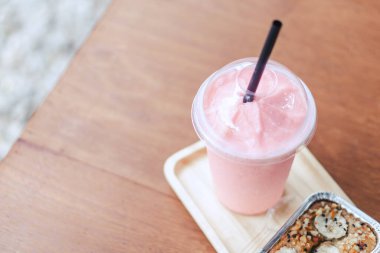Yakın plan çilekli smoothie ve yeşil doğa arka planlı kek, seçici odaklı