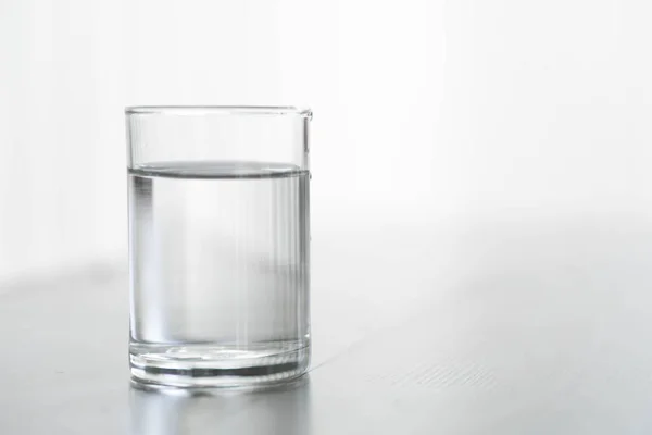 Glass of water on wood table with light in the morning, healthy care concept, selective focus