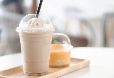 Bir bardak buzlu americano kahvesi ve portakallı keki ahşap masaya koy.