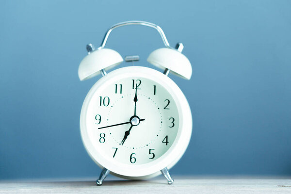 Alarm clock on blue table with soft light in the morning, selective