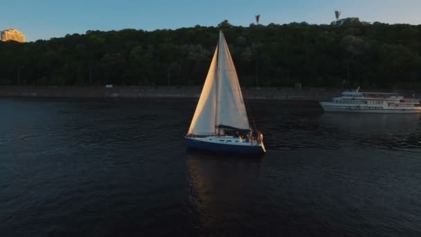 Iate à vela com velas brancas nada ao longo do rio ao pôr do sol antena — Vídeo de Stock