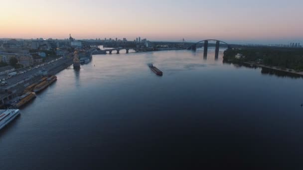 Баржа вітрила вздовж річки поблизу міського порту на заході сонця повітряні кадри — стокове відео