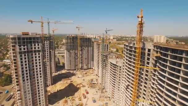 Будівництво будинків. Дрон літає над будівельним майданчиком з баштовими кранами — стокове відео