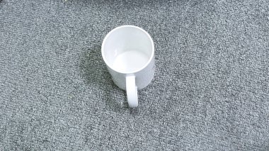 Beyaz kupa, kahve ya da kakao gibi sıcak bir içeceğe hazır gri desenli bir yüzeyde oturur ve bir kafe restoranının tasarımları ya da logoları için model olarak kullanılabilir..
