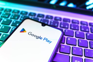 Prag, Çek Cumhuriyeti - 08 19 2025: Google Play logosunu gösteren klavyenin üzerinde duran bir cep telefonunun yakından görüntüsü. Google Play uygulamaları, oyunları ve dijital içeriği indirmek için bir platformdur.