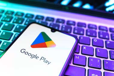 Prag, Çek Cumhuriyeti - 08 19 2025: Google Play logosunu gösteren klavyenin üzerinde duran bir cep telefonunun yakından görüntüsü. Google Play uygulamaları, oyunları ve dijital içeriği indirmek için bir platformdur.