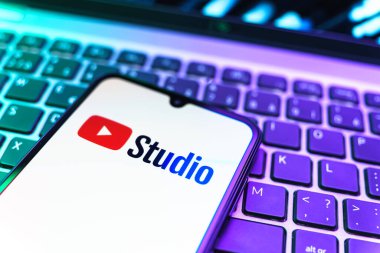 Prag, Çek Cumhuriyeti - 08 19 2025: Youtube Stüdyo logosunu gösteren klavyenin üzerinde duran cep telefonunun yakından görüntüsü. Youtube Studio YouTube kanallarını yönetmek ve analiz etmek için bir platformdur.