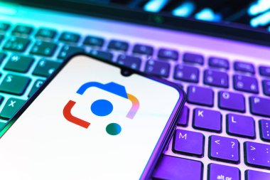 Prag, Çek Cumhuriyeti - 08 19 2025: Google Lens logosunu gösteren klavyenin üzerinde duran cep telefonunun yakından görüntüsü. Google Lens, resimlerdeki görsel arama ve bilgi için kullanılan bir araçtır..