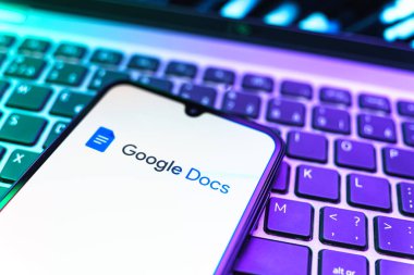 Prag, Çek Cumhuriyeti - 08 19 2025: Google Docs logosunu gösteren klavyenin üzerinde duran cep telefonunun yakından görüntüsü. Google Docs metin belgeleri oluşturmak ve düzenlemek için bir platformdur.