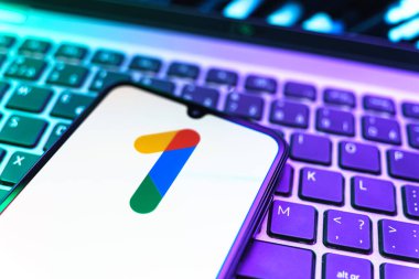 Prag, Çek Cumhuriyeti - 08 19 2025: Bir klavyenin üzerinde duran ve Google One logosunu gösteren cep telefonunun yakından görüntüsü. Google 1 bulut depolama ve abonelik hizmetleri için bir platformdur.
