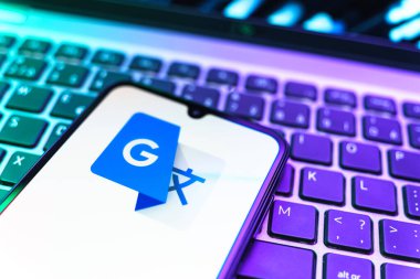 Prag, Çek Cumhuriyeti - 08 19 2025: Google Translate logosunu gösteren klavyenin üzerinde duran cep telefonunun yakından görüntüsü. Google Çevirisi metni ve konuşmayı diller arası çevirmek için bir platformdur..