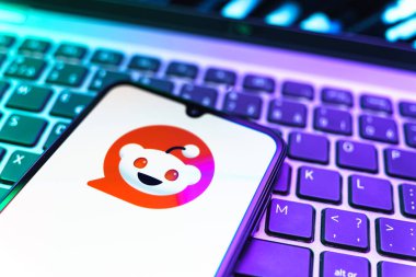 Prag, Çek Cumhuriyeti - 08 19 2025: Bir klavyenin üzerinde duran ve Reddit logosunu gösteren cep telefonunun yakından görüntüsü. Reddit tartışma, haber ve toplum içeriği için bir platformdur.