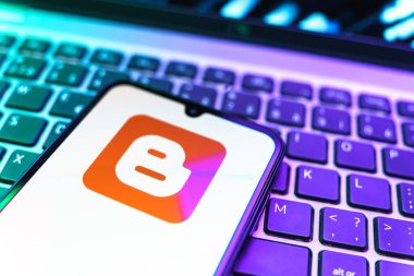 Prag, Çek Cumhuriyeti - 08 19 2025: Klavyenin üzerinde duran ve Blogger logosunu gösteren cep telefonunun yakından görüntüsü. Blogger blog oluşturma ve yayınlama için bir platformdur.