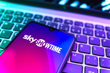 Prag, Çek Cumhuriyeti - 08 19 2025: SkyShowtime logosunu gösteren klavyenin üzerinde duran cep telefonunun yakından görüntüsü. SkyShowtime, sinema ve televizyon dizileri için bir yayın platformudur..