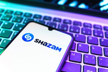 Prag, Çek Cumhuriyeti - 08 19 2025: Klavyede duran ve Shazam logosunu gösteren bir cep telefonunun yakından görüntüsü. Shazam şarkıları ve müzik parçalarını tanımlamak için bir uygulamadır.
