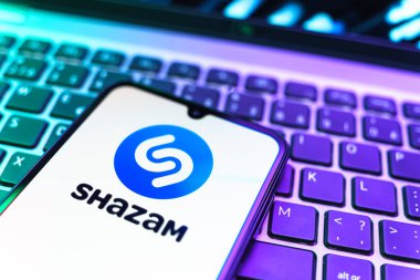 Prag, Çek Cumhuriyeti - 08 19 2025: Klavyede duran ve Shazam logosunu gösteren bir cep telefonunun yakından görüntüsü. Shazam şarkıları ve müzik parçalarını tanımlamak için bir uygulamadır.