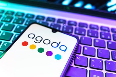 Prag, Çek Cumhuriyeti - 08 19 2025: Cep telefonunun klavyede duran ve Agoda logosunu gösteren yakın plan görüntüsü. Agoda, otelleri ve seyahat yerlerini ayırtmak için bir platform..