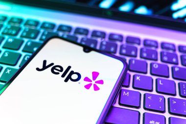 Prag, Çek Cumhuriyeti - 08 19 2025: Klavyede duran ve Yelp logosunu gösteren bir cep telefonunun yakından görüntüsü. Yelp yerel işletmeleri bulmak ve incelemek için bir platformdur.