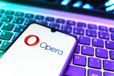 Prag, Çek Cumhuriyeti - 08 19 2025: Opera logosunu gösteren klavyenin üzerinde duran cep telefonunun yakından görüntüsü. Opera hızlı ve güvenli internet taraması için bir web tarayıcısıdır.