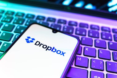 Prag, Çek Cumhuriyeti - 08 19 2025: Dropbox logosunu gösteren klavyenin üzerinde duran cep telefonunun yakından görüntüsü. Dropbox bulut depolama ve dosya paylaşımı için bir platformdur.