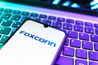 Prag, Çek Cumhuriyeti - 08 19 2025: Foxconn logosunu gösteren klavyenin üzerinde duran cep telefonunun yakından görüntüsü. Foxconn elektronik ve parça üreten bir şirket..