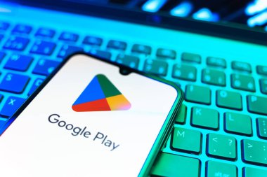 Prag, Çek Cumhuriyeti - 08 19 2025: Google Play logosunu gösteren klavyenin üzerinde duran bir cep telefonunun yakından görüntüsü. Google Play uygulamaları, oyunları ve dijital içeriği indirmek için bir platformdur.