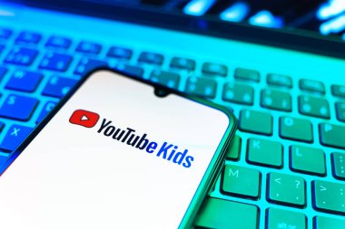 Prag, Çek Cumhuriyeti - 08 19 2025: Klavyede duran ve Youtube Kids logosunu gösteren cep telefonunun yakından görüntüsü. Youtube Kids çocuk dostu video içeriği için bir platformdur.