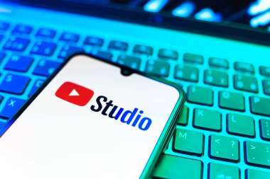 Prag, Çek Cumhuriyeti - 08 19 2025: Youtube Stüdyo logosunu gösteren klavyenin üzerinde duran cep telefonunun yakından görüntüsü. Youtube Studio YouTube kanallarını yönetmek ve analiz etmek için bir platformdur.