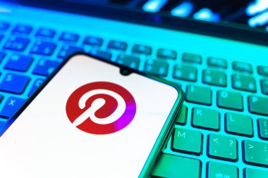 Prag, Çek Cumhuriyeti - 08 19 2025: Pinterest logosunu gösteren klavyenin üzerinde duran cep telefonunun yakından görüntüsü. Pinterest fikirleri görsel olarak keşfetmek ve kaydetmek için bir platformdur..