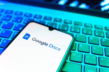 Prag, Çek Cumhuriyeti - 08 19 2025: Google Docs logosunu gösteren klavyenin üzerinde duran cep telefonunun yakından görüntüsü. Google Docs metin belgeleri oluşturmak ve düzenlemek için bir platformdur.