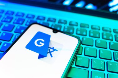 Prag, Çek Cumhuriyeti - 08 19 2025: Google Translate logosunu gösteren klavyenin üzerinde duran cep telefonunun yakından görüntüsü. Google Çevirisi metni ve konuşmayı diller arası çevirmek için bir platformdur..